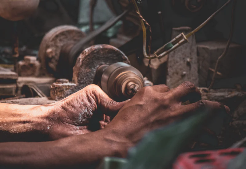 Mains d'artisan façonnant une pièce métallique